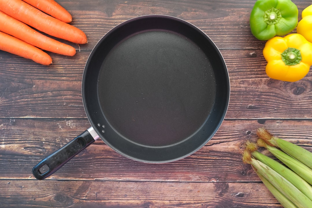 A close-up of a nonstick frying pan on a kitchen countertop with cooking utensils nearby.